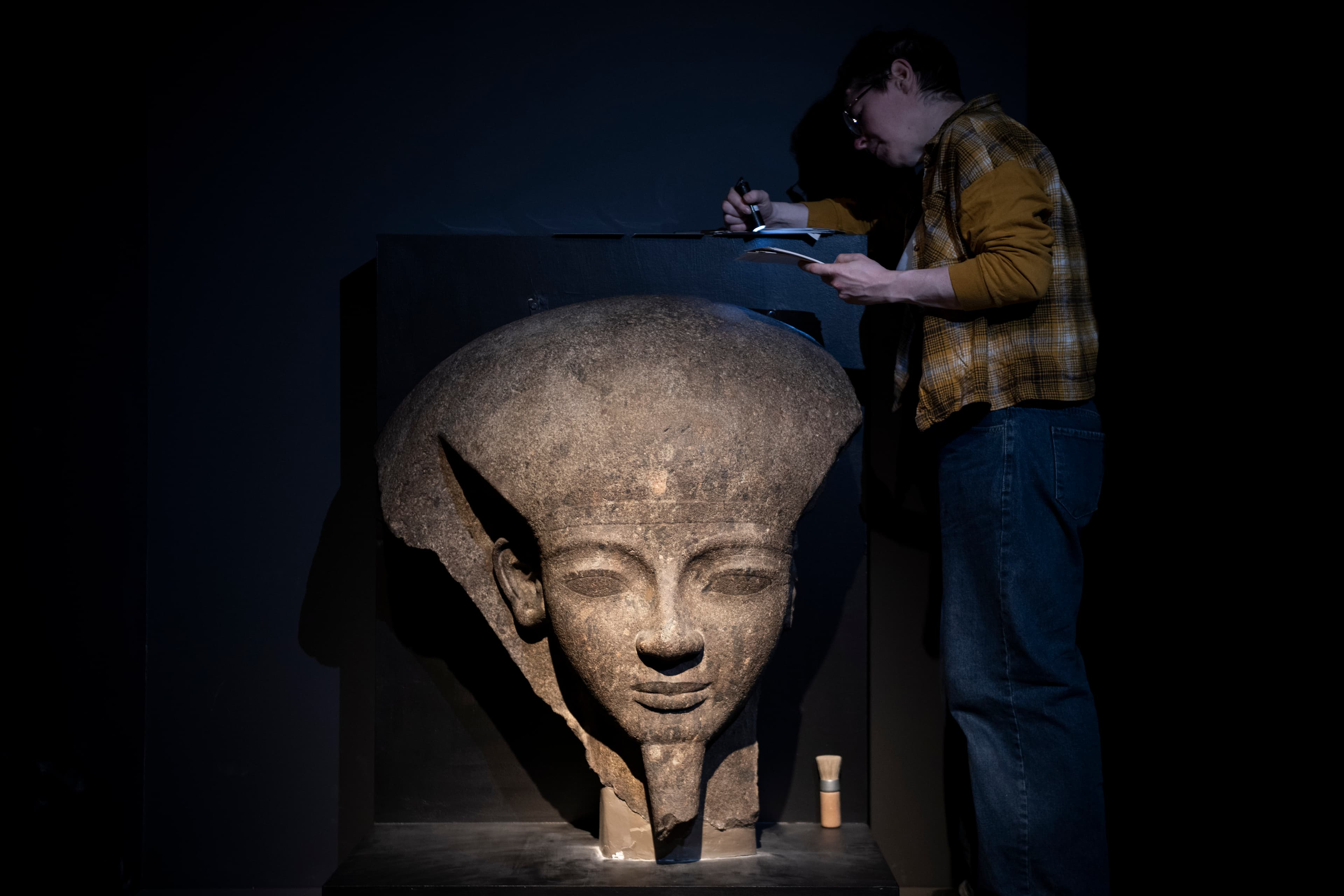 大英博物館工作人員在展出前檢視展品〈拉美西斯六世的石棺蓋殘片〉。（奇美博物館提供）
