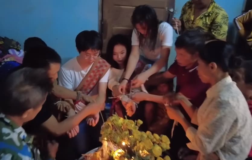 網紅林老師與寮國嫩妻在當地舉辦婚禮,眾人在他們手上綁繩祝福。(翻攝YT頻道「林老师的旅行)