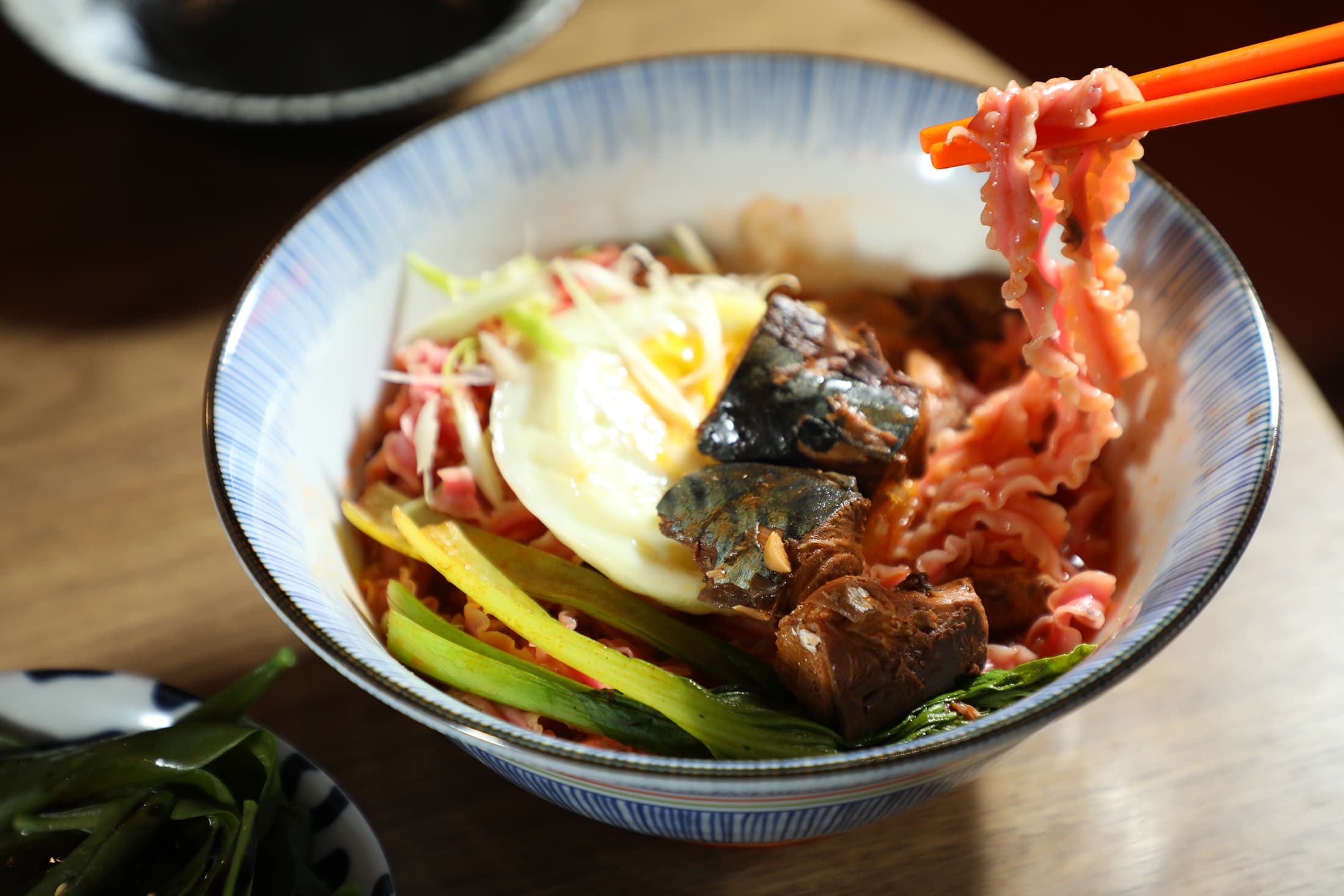 夜宵森食屋發想自「颱風麵」的「茄汁鯖魚麵」,除魚罐頭、蔬菜與雞蛋等標配,還選用屏東製作的紅龍果麵。(150元/碗)
