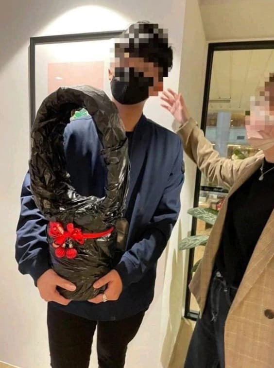 男子參加交換禮物活動,興奮抱著用垃圾袋包裝的禮物。(翻攝臉書社團「爆廢1公社」)