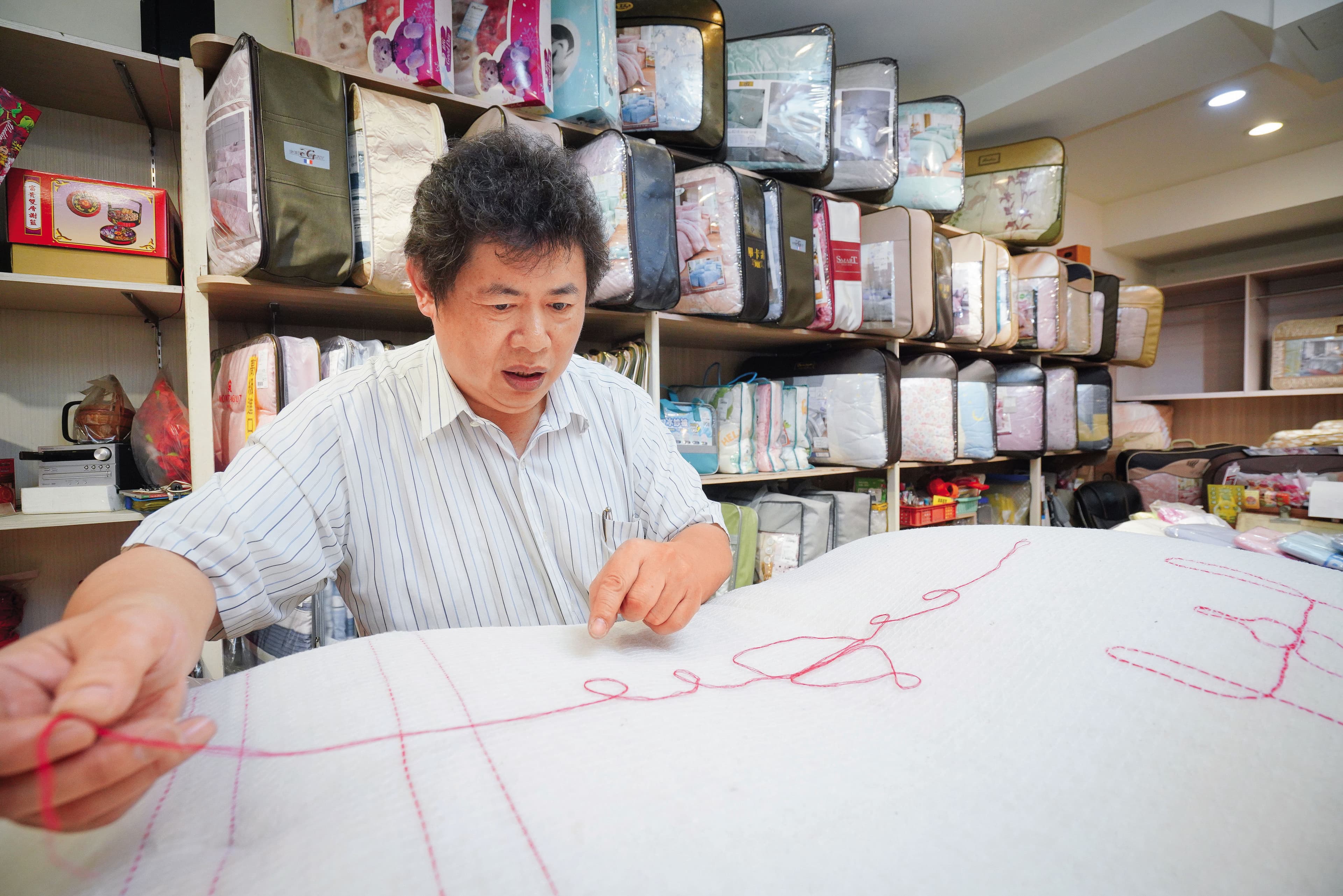 古代手工棉被行普遍沒有店名，師傅以自創商標識別。張寶仁示範祖傳「葫蘆」標誌如何編織。