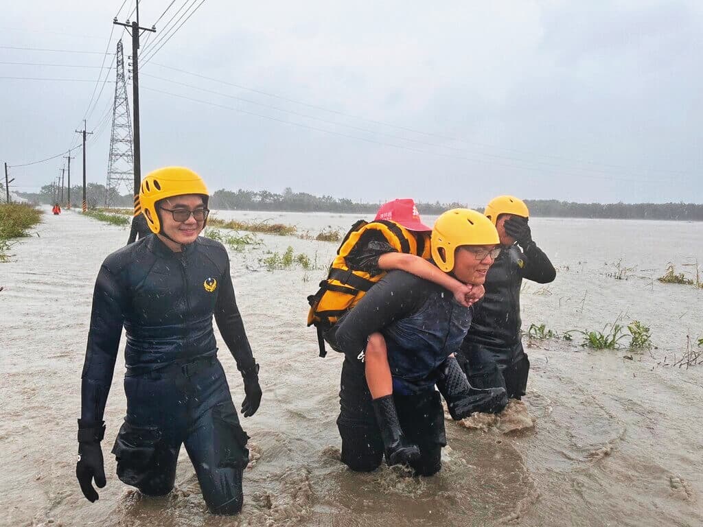 南台灣暴雨導致大淹水,消防隊員冒險涉水救出受困者。(屏東消防局提供)