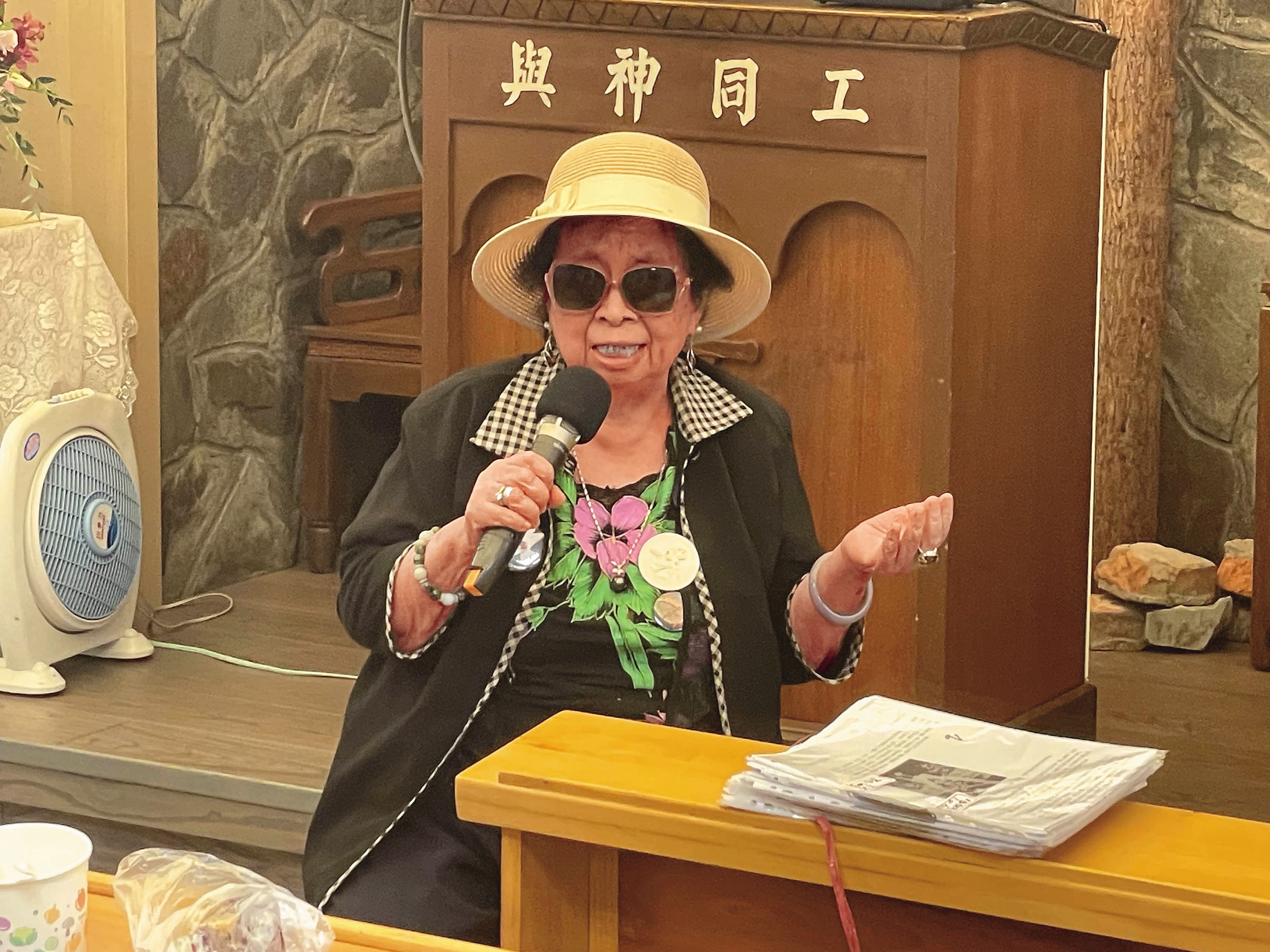 2024年6月,義光教會播放紀錄片《牽阮的手》時,田孟淑受邀在台前分享。她面前一疊紙,是精心製作的新聞紀念冊。(王銘澤提供)