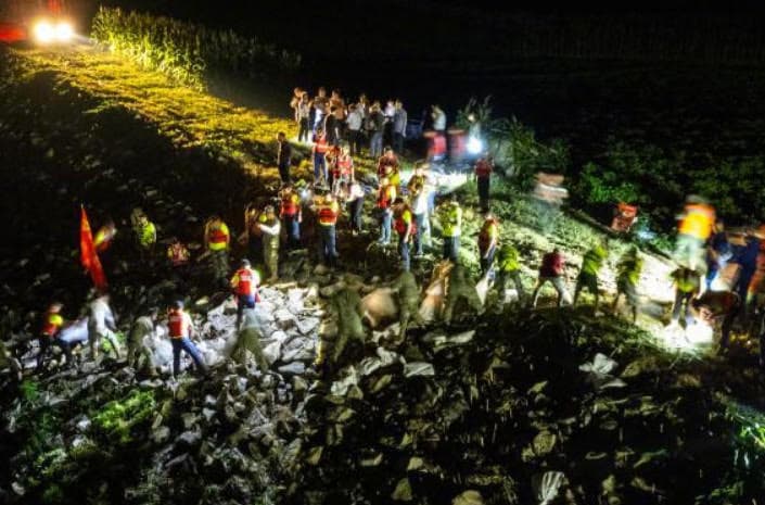 當地政府調度砂石與大型機具搶險,封堵洞庭湖潰堤口。(翻攝微博)