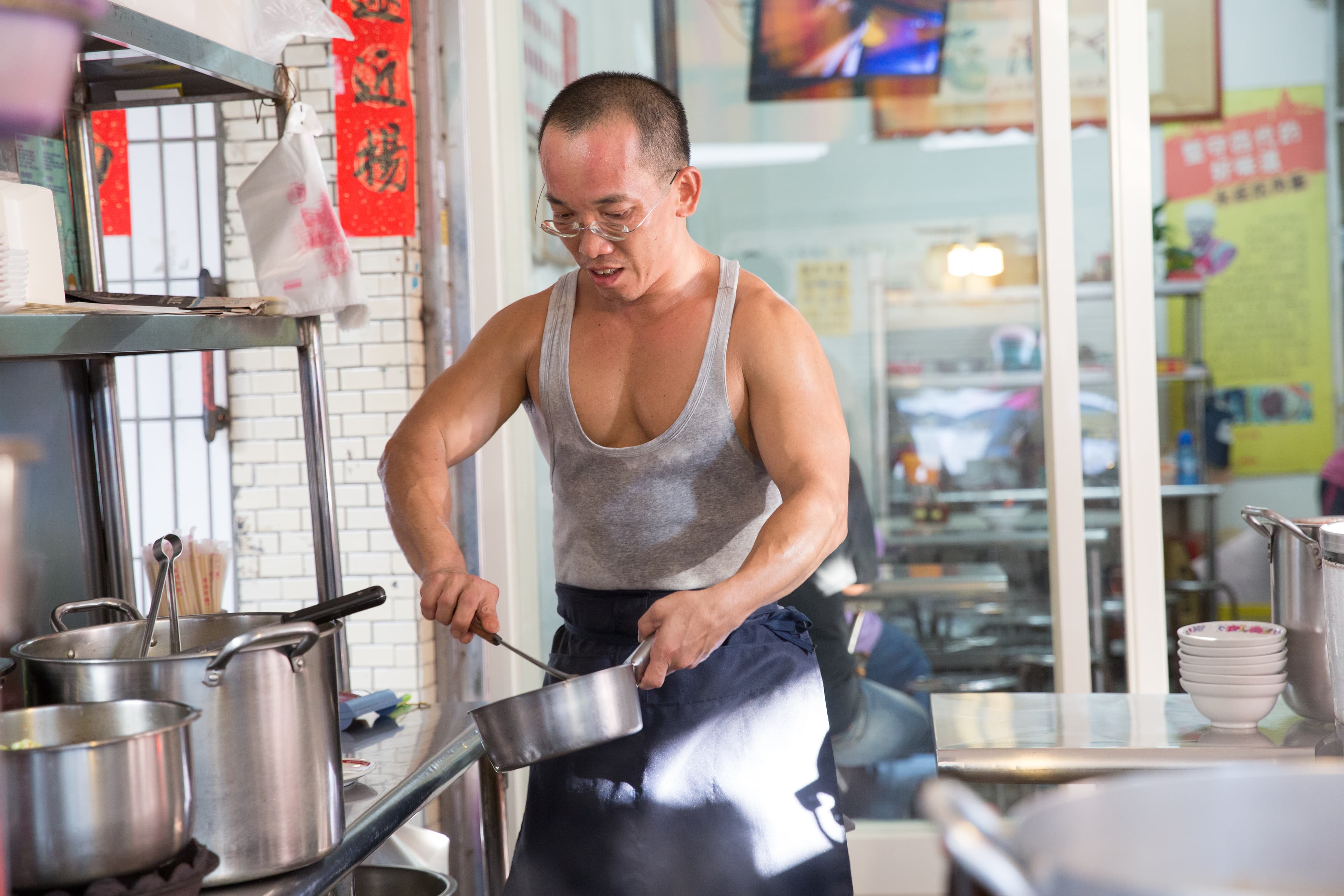 永成炕肉飯的攤頭特別乾淨,尤其大小鍋具都擦得清潔溜溜。圖為鄧永成長子鄧志凌。