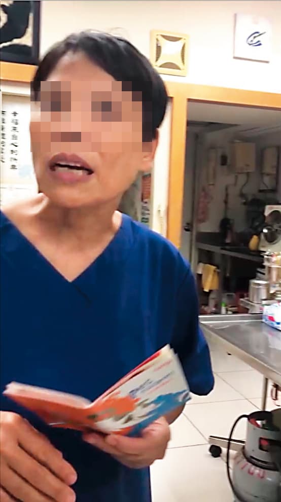 身穿藍衣拿著狗狗健康護照為寵物進行檢診的是「無照女獸醫」林美玲。(讀者提供)
