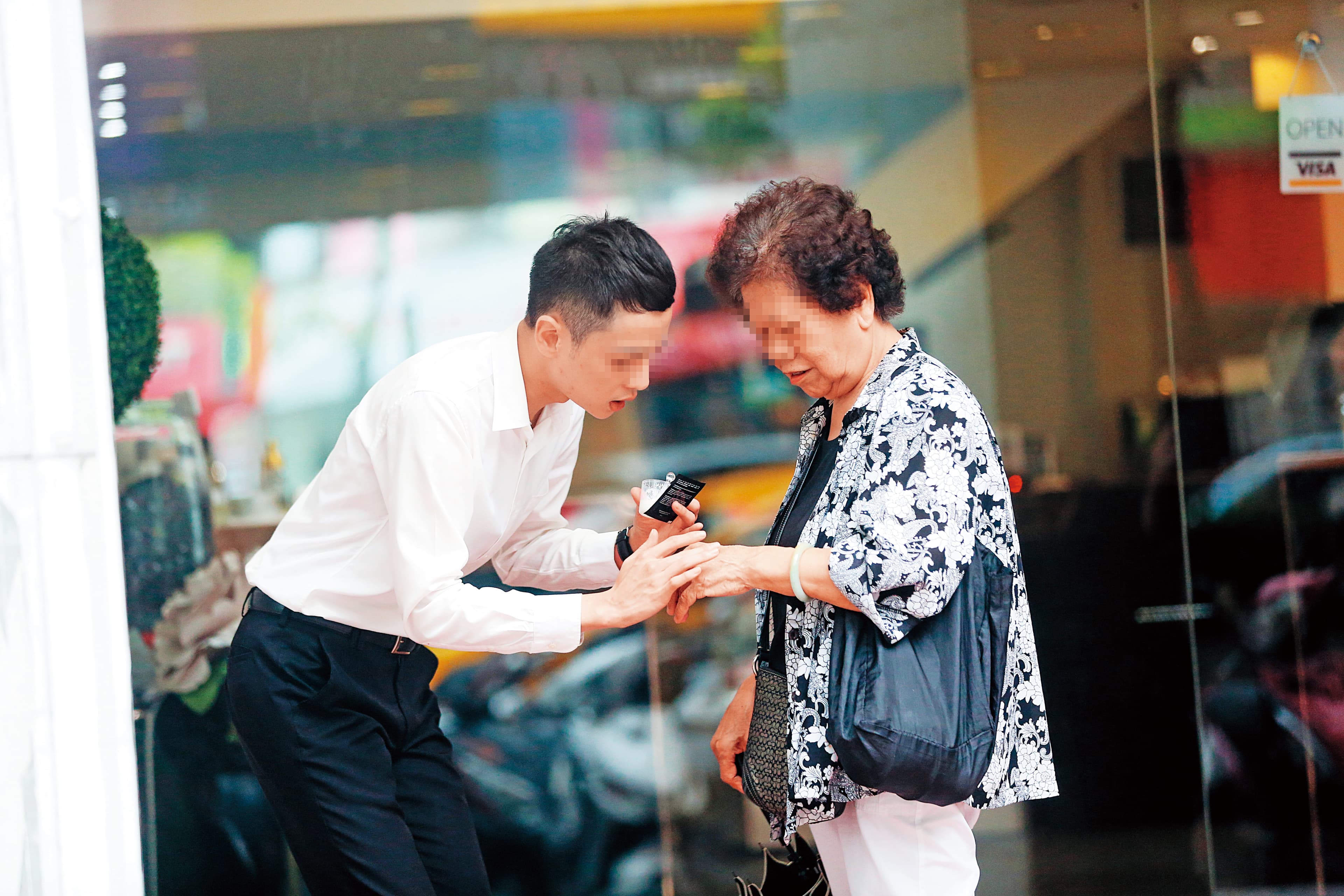 美妝店的男店員在路邊攬客,直接把保養品塗抹在路過的婦人手上。