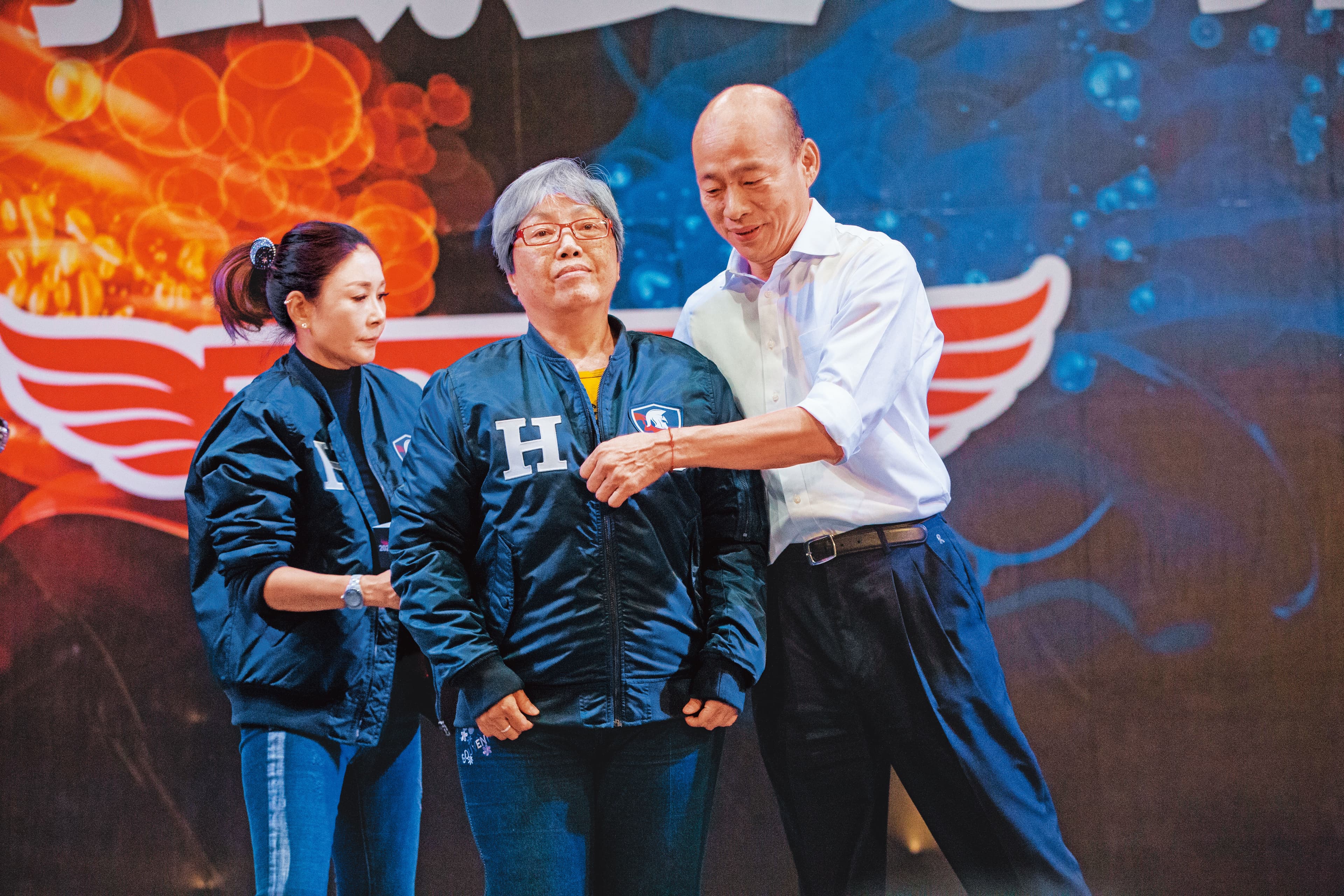 韓國瑜(右)日前賣出身上的「原味飛行夾克」,高雄謝女士(中)出價100萬元得標,她直呼:「好幸福。」