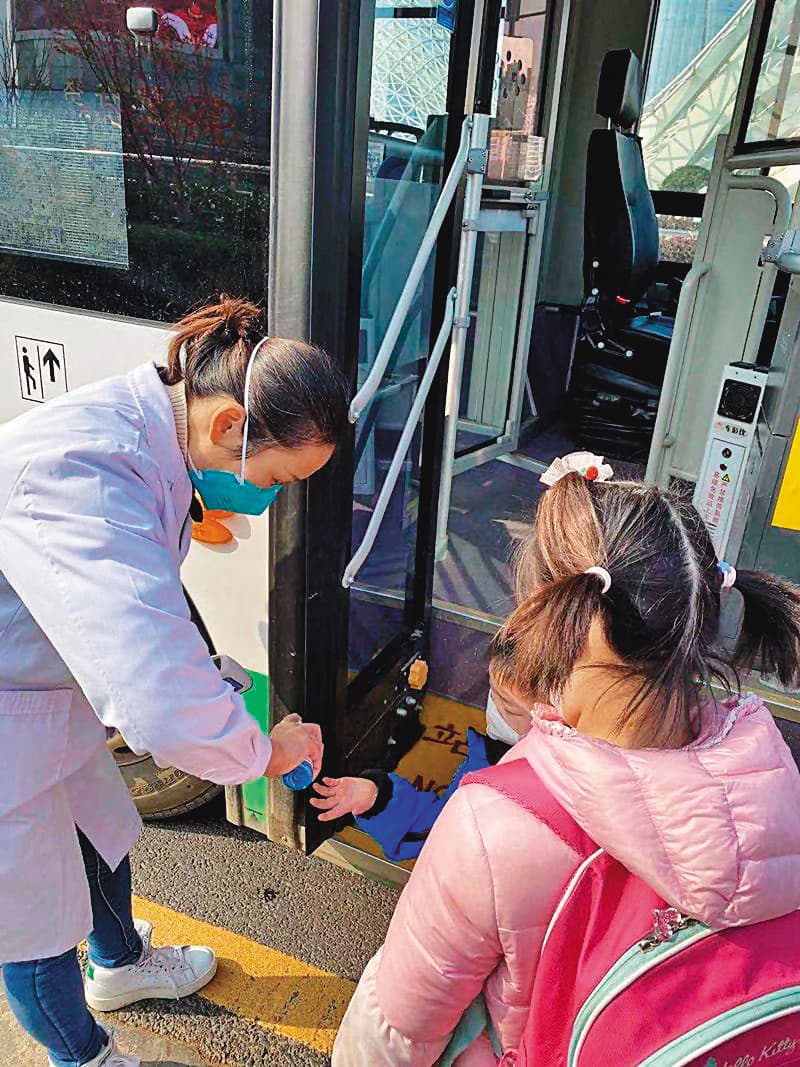 首批武漢返台專機3日夜間飛抵台灣。圖為2名首批返台兒童上武漢的接駁車前消毒雙手。(台北家長會長協會提供)