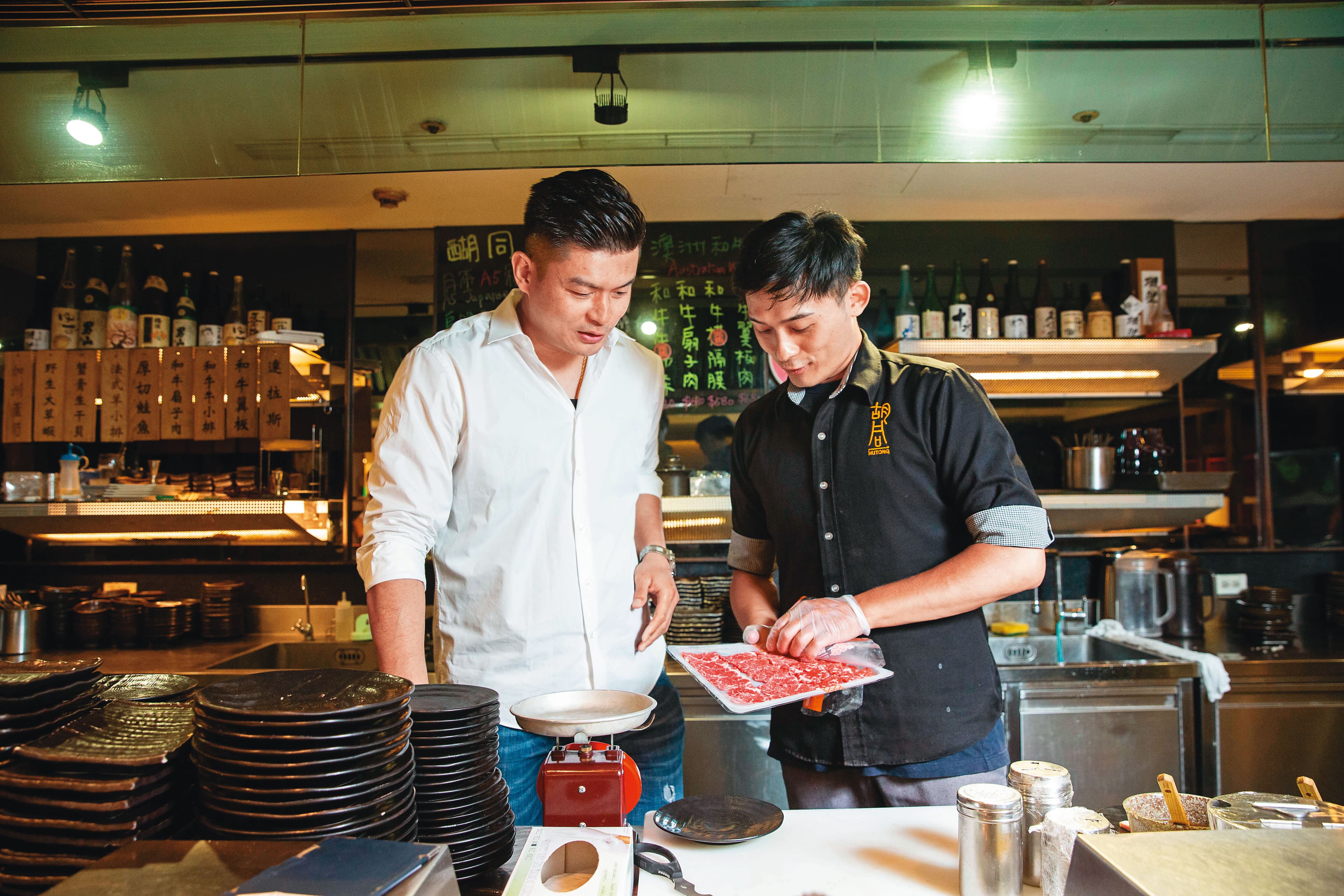 吳念忠(左)巡視店面時,再次檢視肉品品質是否合格。