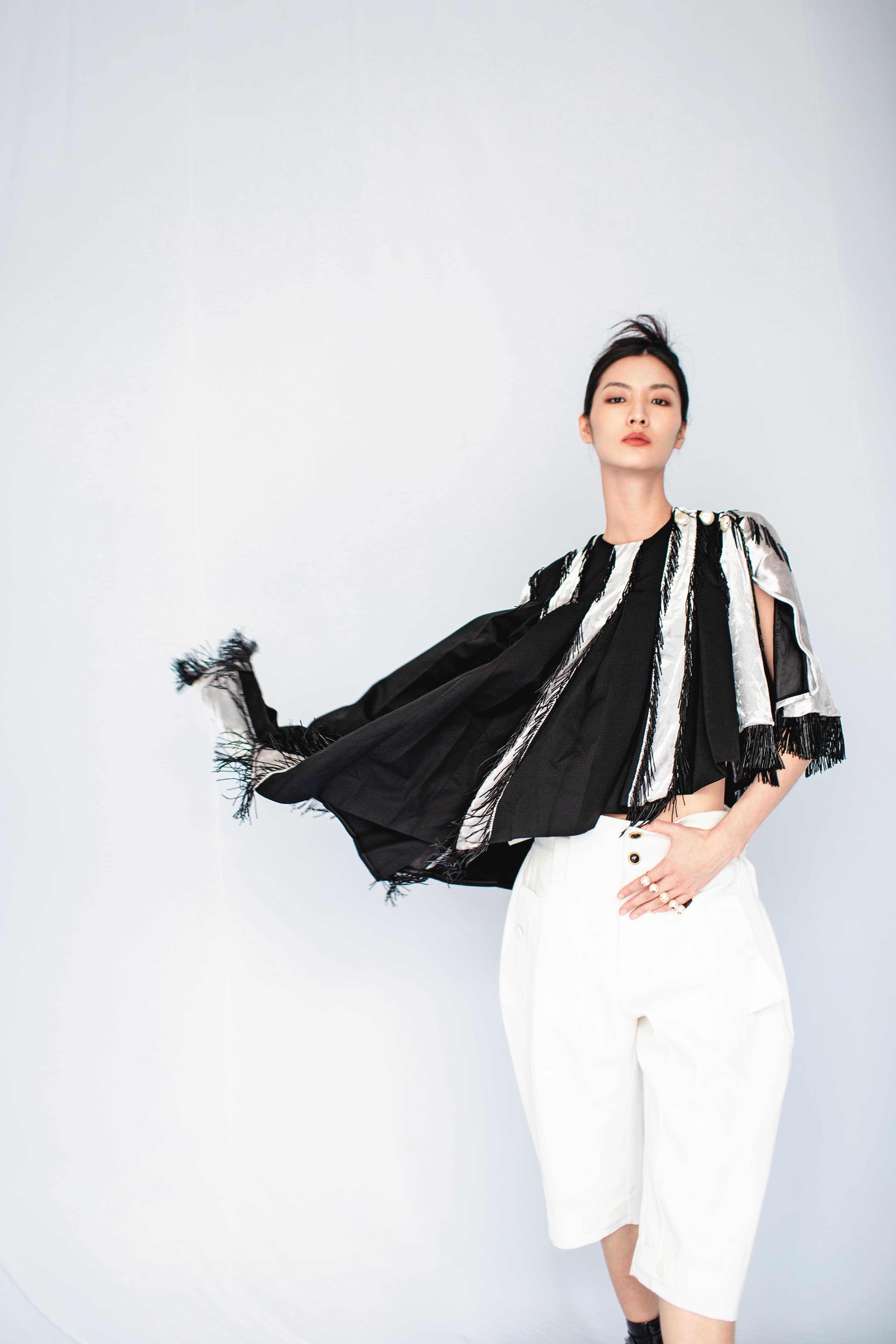 拼接斗篷NT$140,000 by LOUIS VUITTON;短版背心NT$9,700 by LOUIS VUITTON;寬版百慕達褲NT$21,700 by LOUIS VUITTON;珍珠指間戒,價格店洽 by VALENTINO GARAVANI。