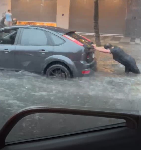 北市重慶北路積水成河,有汽機車駕駛疑似因愛車拋錨下車推行。(翻攝自記者爆料網)