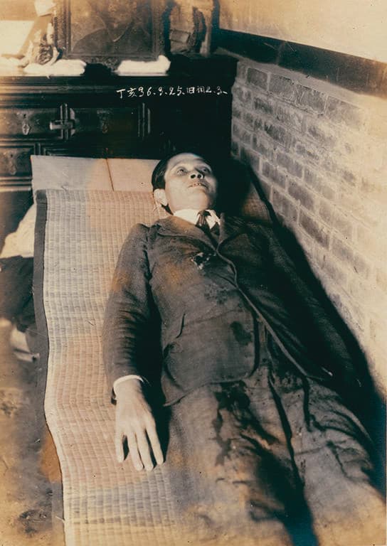 陳澄波遺照裡的張捷,蹲著扛住門板,讓攝影師拍陳澄波遺容。(財團法人陳澄波文化基金會提供)
