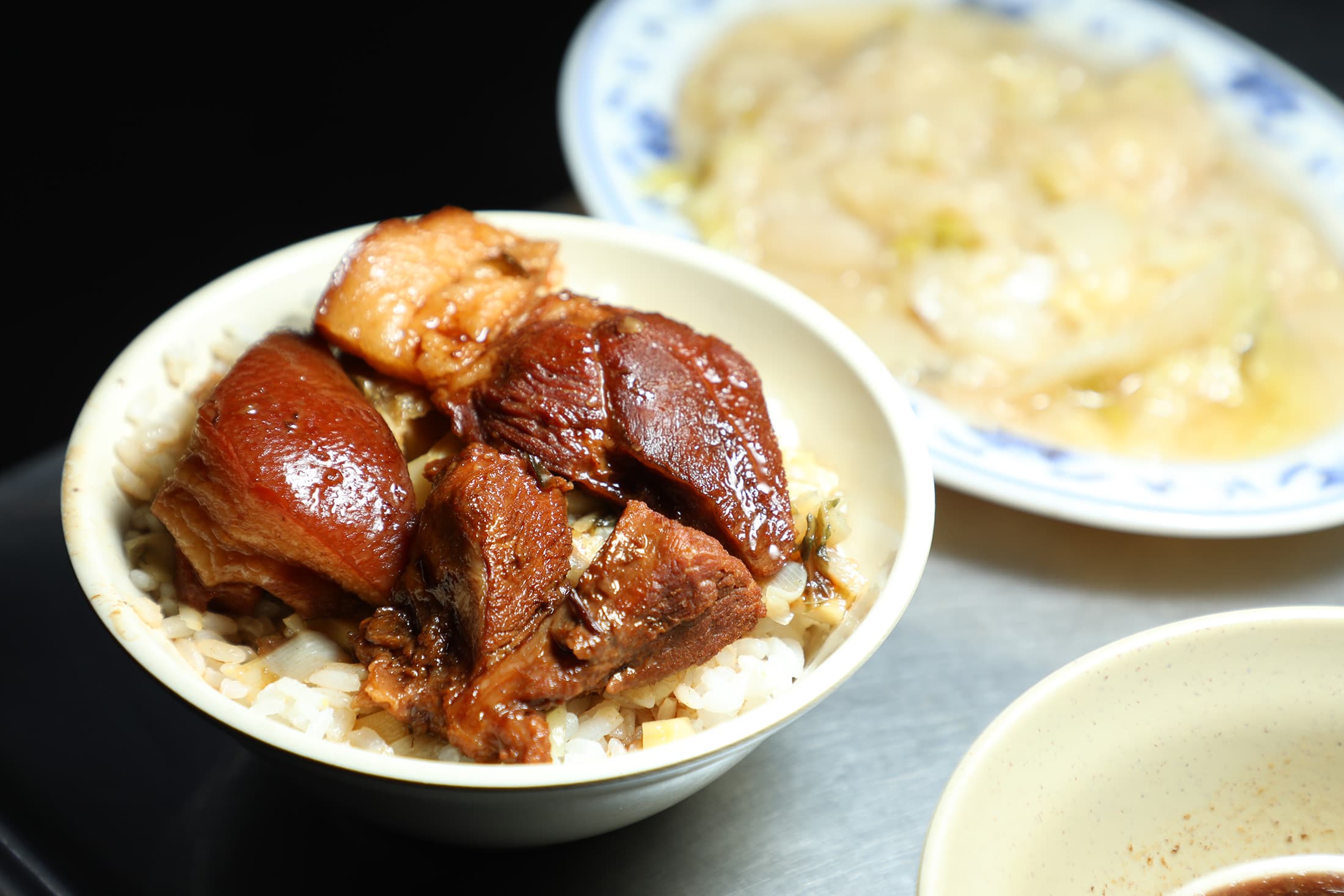 「焢肉飯」(前,60元/份)放上幾塊帶皮肥肉與瘦肉,米飯淋上醇厚滷汁,再點份「滷白菜」(後,35元/份),就是簡單卻讓人感到滿足的組合。
