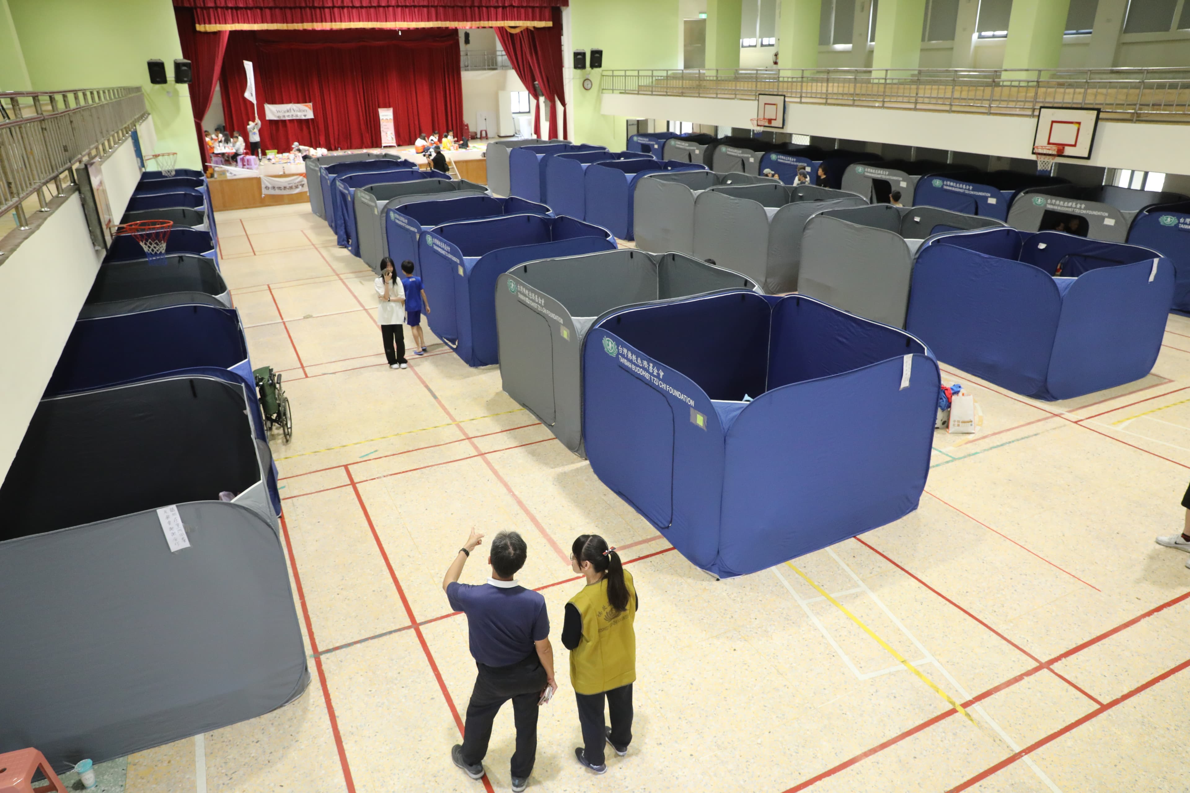 慈濟基金會在國小體育館架設「淨斯福慧環保隔屏」,提供災民隱私空間。