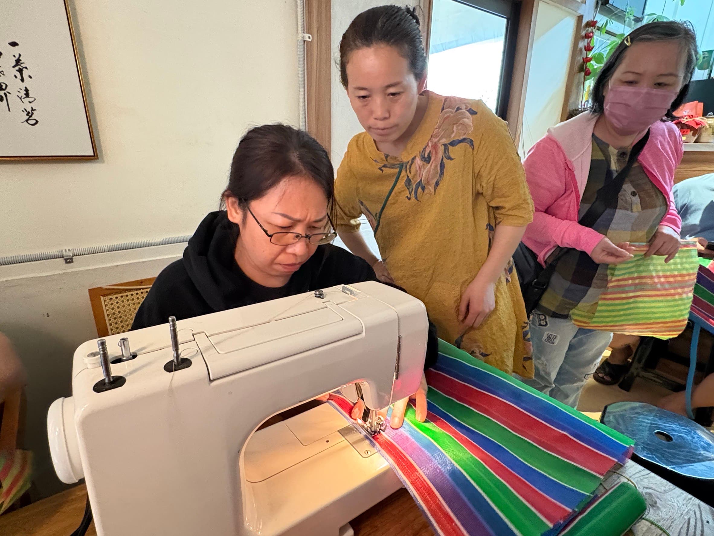 講師張勤(中)指導新住民阮氏錢(左)使用縫紉機縫製茄芷袋。(移民署提供)