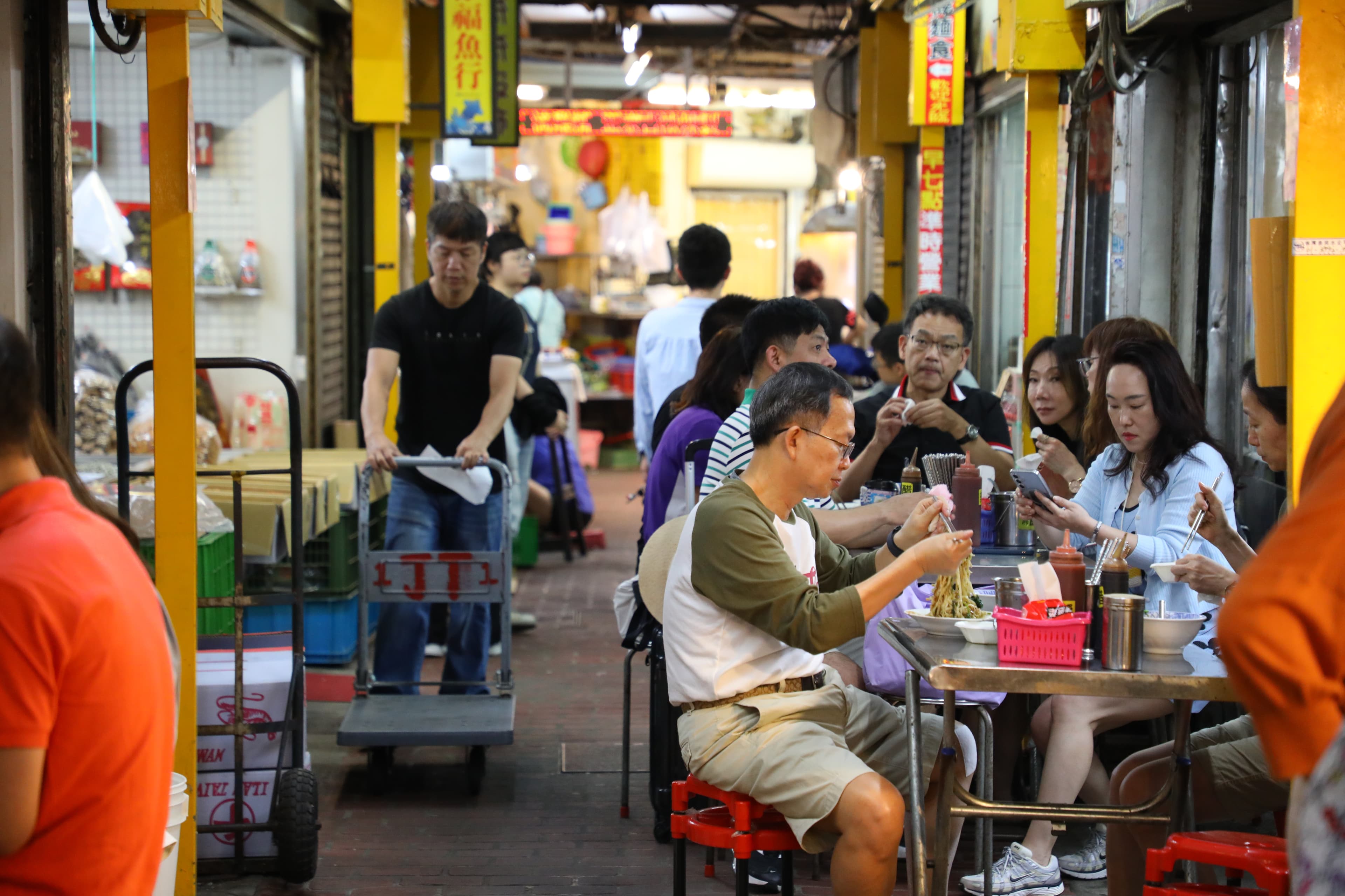 食客們坐在擺在走道上的簡陋桌椅,開心地大快朵頤。