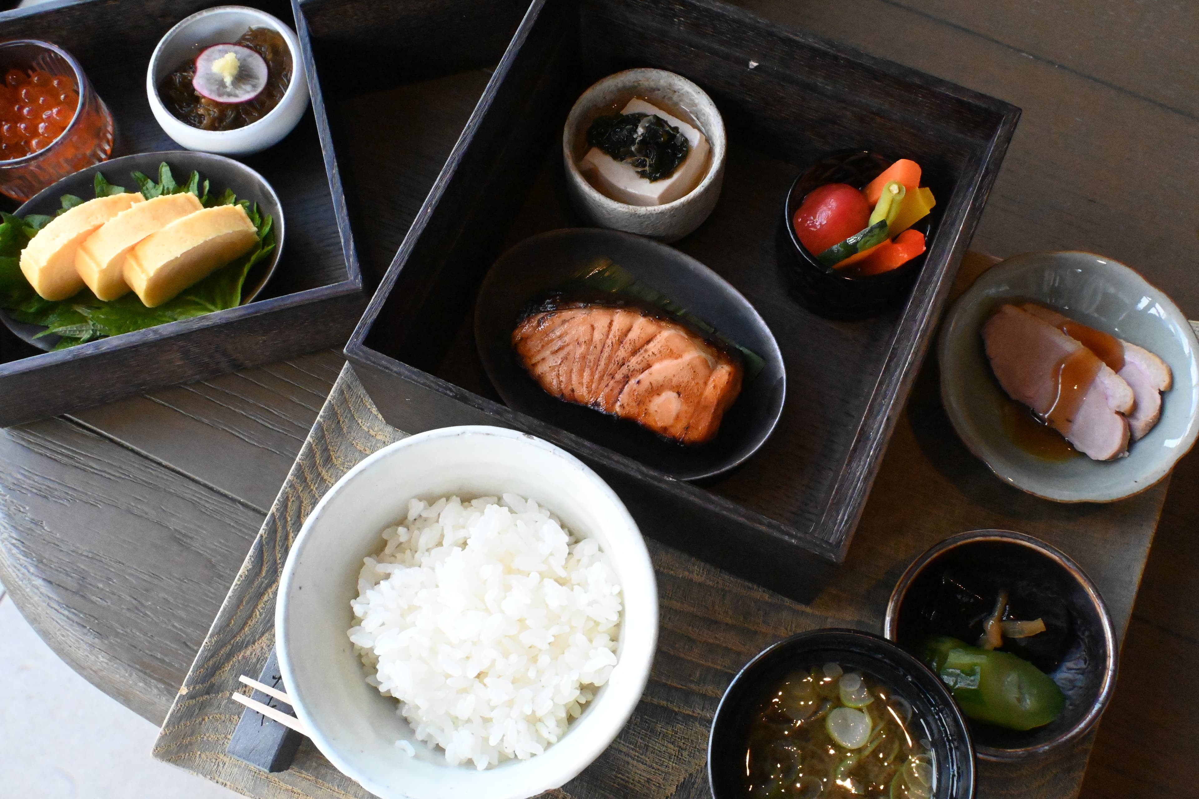 NAGI的日式早餐「Japanese」包含烤鮭魚、時令燉蔬菜、日式玉子燒搭配蘿蔔泥、花生豆腐佐柴魚片、黑醋海藻(もずく)、醃漬蔬菜等多道小菜,搭配白飯與味噌湯。(日幣8,000元/份,約NT$1516)