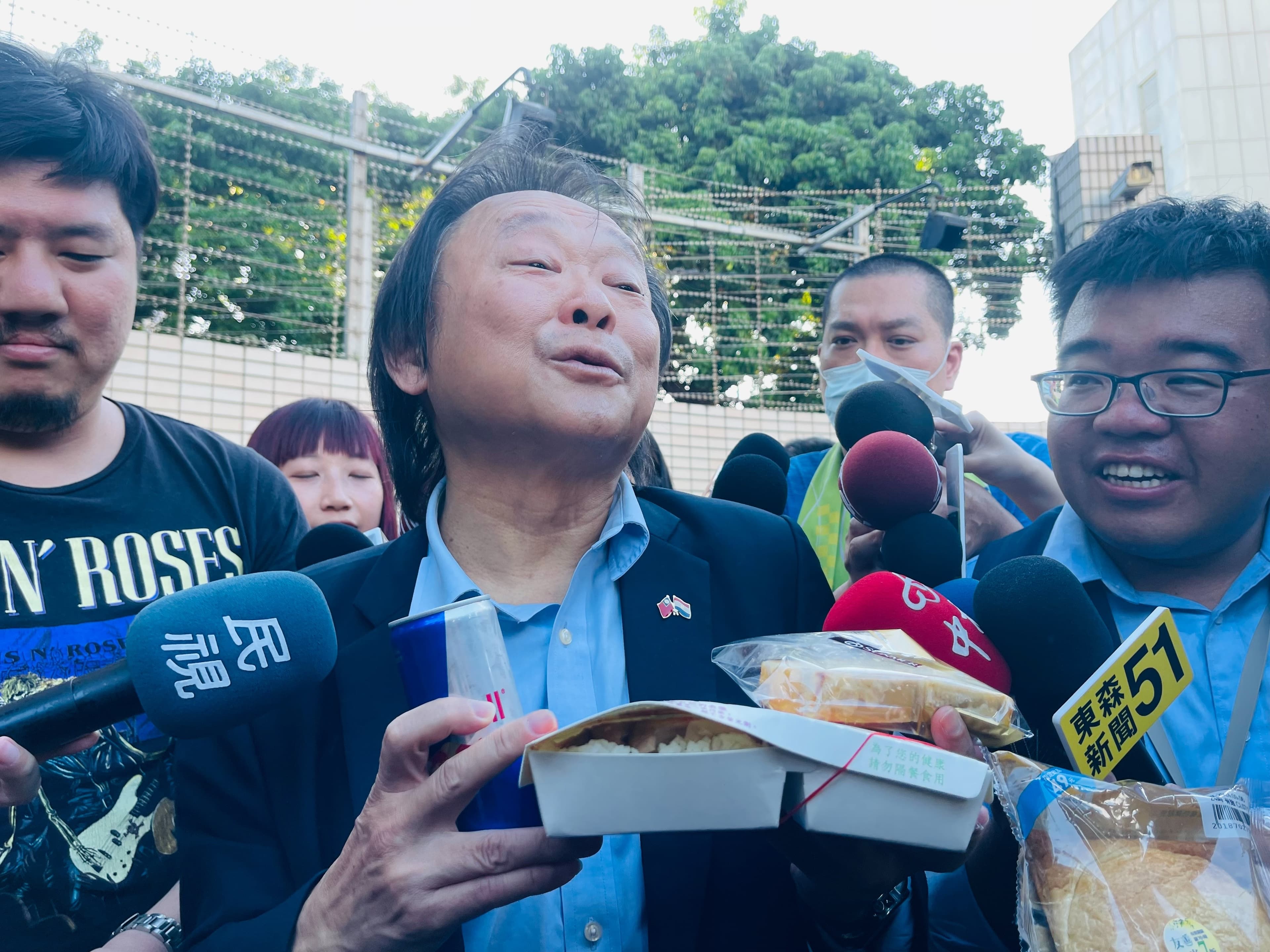 王世堅手持雞鴨便當、起酥蛋糕、能量飲料,還有要送給柯文哲室友的麵包。
